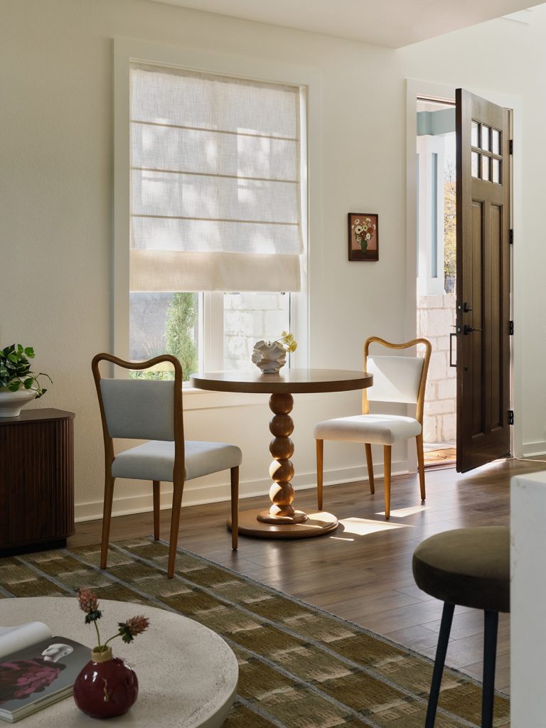 Sunlit dining nook in Drew Lane model home with round wood table, upholstered chairs, and soft neutral tones