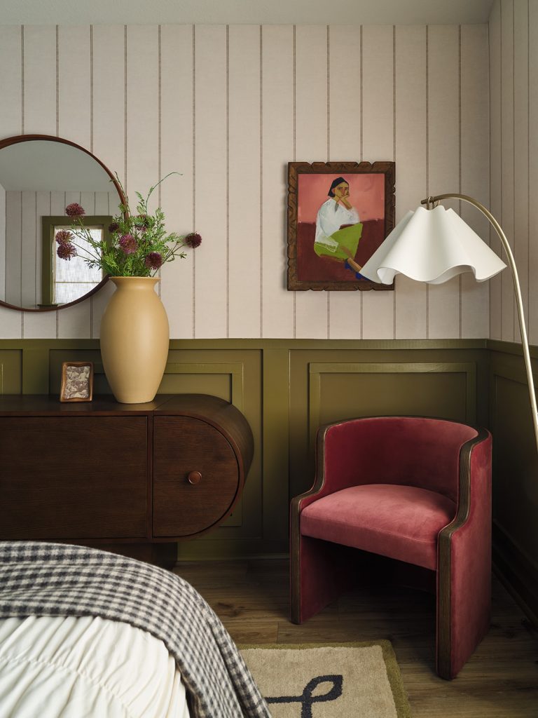 Bold color vignette with red accent chair, green paneled wall, and vintage artwork in Drew Lane model home